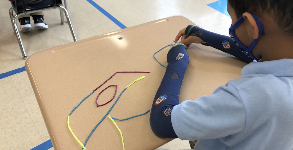 A Syracuse Academy of Science and Citizenship student creates shapes using string as part of a math lesson.