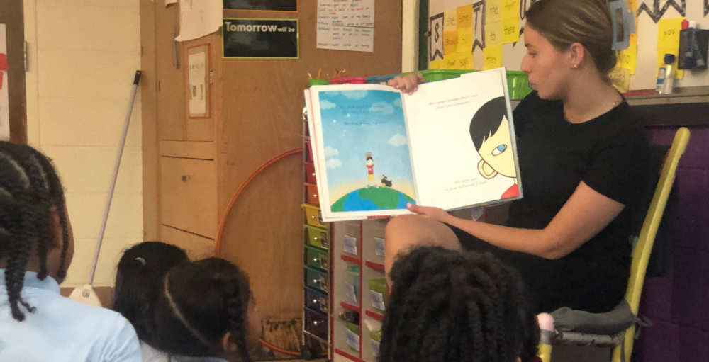 Student Teacher, Ms. H, reads the story book, ‘We’re All Wonders’ to the Syracuse Academy of Science and Citizenship elementary school 2nd-grade students.